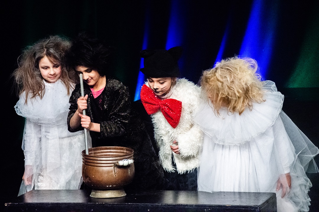 Vier verkleidete Kinder auf der Bühne, Szene aus dem Theaterstück.