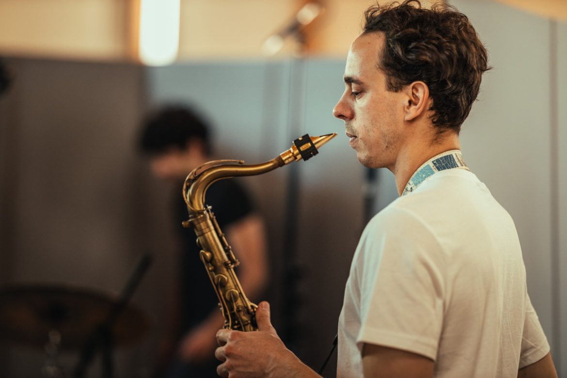 Mensch in weißem TShirt mit Saxophon