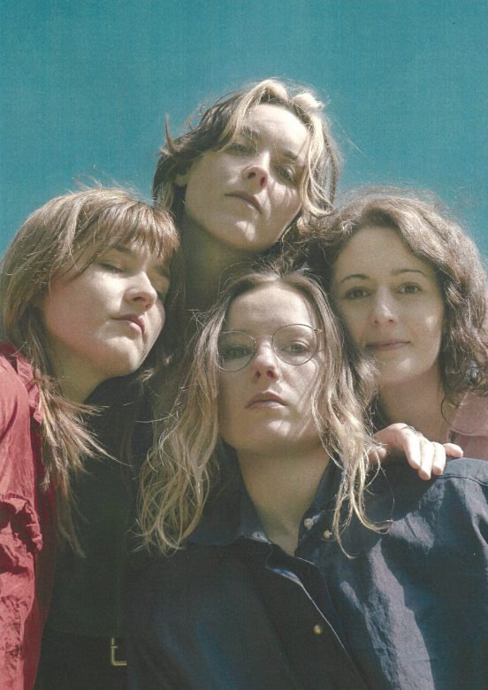 Die vier Künstlerinnen sehen in die Kamera, sie setehen nah bei einander.