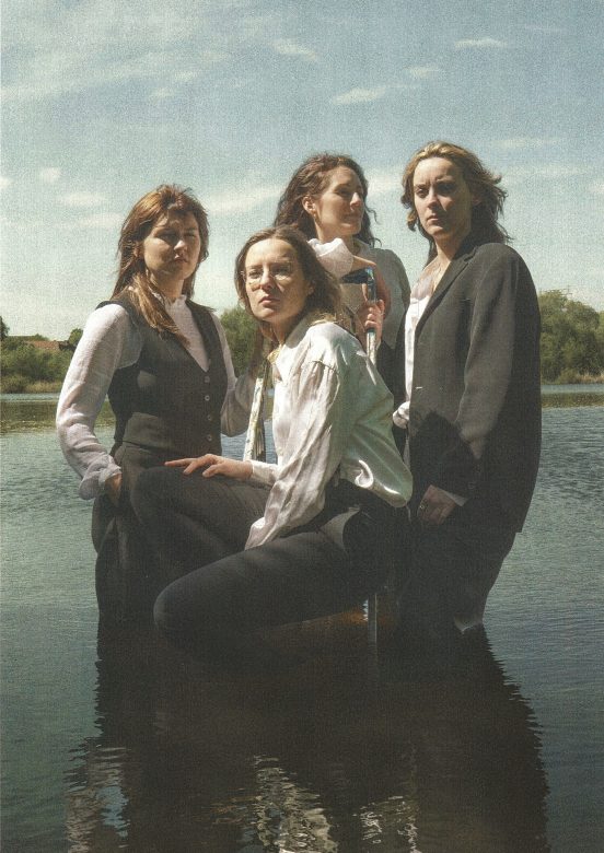 Die vier Künstlerinnen sehen in die Kamera, sie setehen nah bei einander.