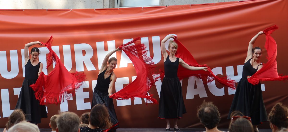 vier Tänzerinnen tanzen mit roten Tüchern auf einer Open-Air-Bühne
