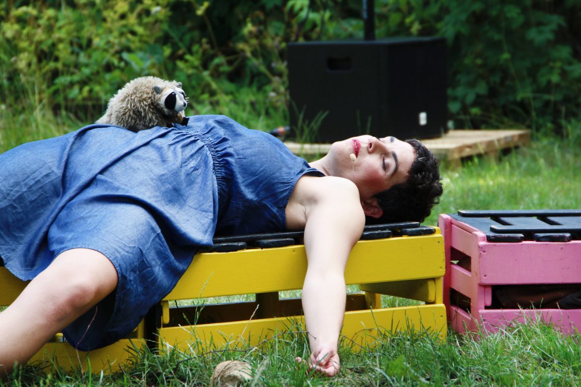 Eine Schauspielerin schläft in einem Garten.