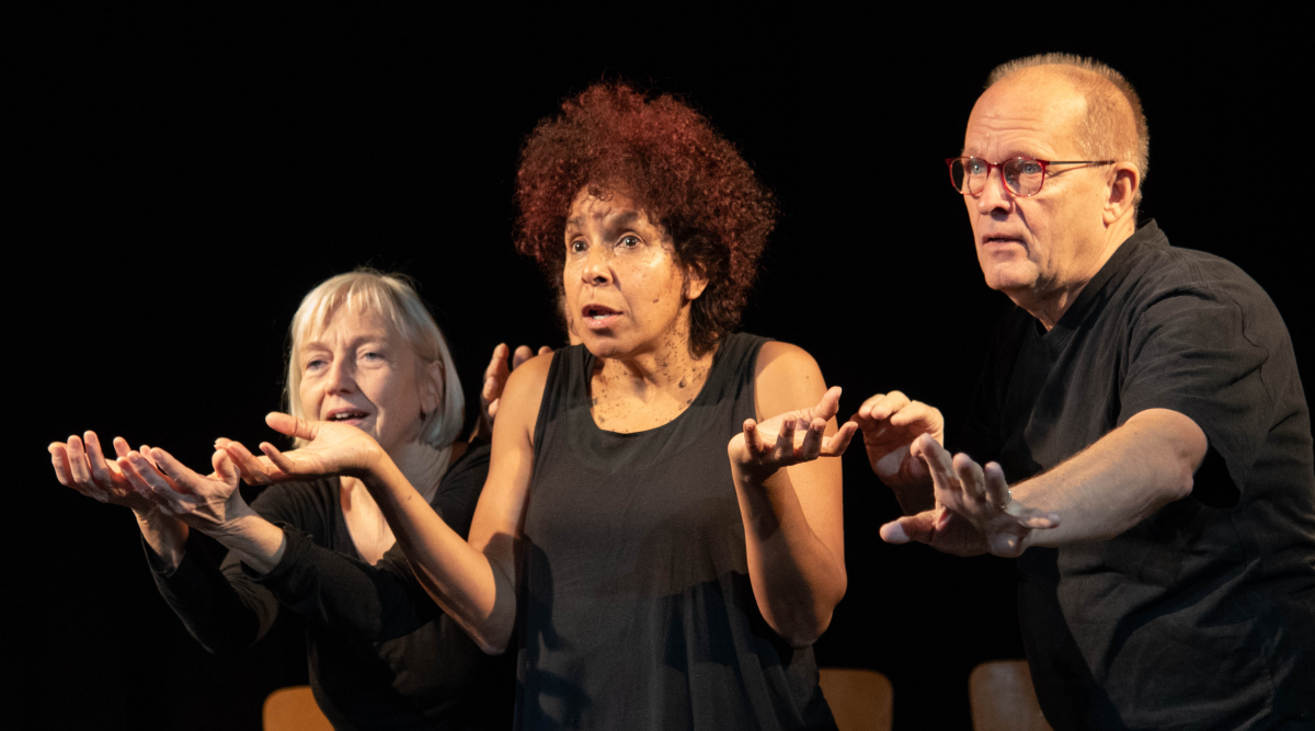 Drei Schauspieler stehen nebeneinander auf der Bühne, sie drücken mit verschienene Emotionen aus: vorsichtige Abwehr, unenschlossene Ratlosigkeit, dankbare Hinwendung.